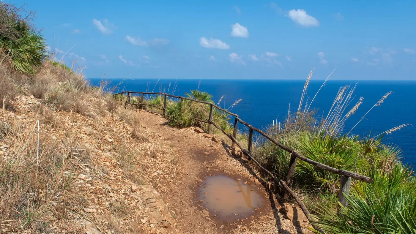 A breathtaking coastal trail along the cliffs of Scopello, Sicily, overlooking the vibrant Mediterranean Sea.