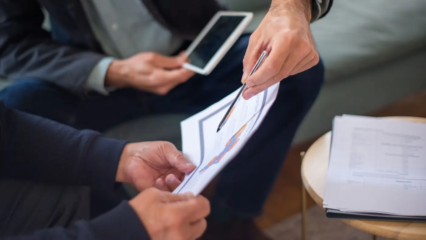 Close-up of two business professionals discussing documents in a meeting.