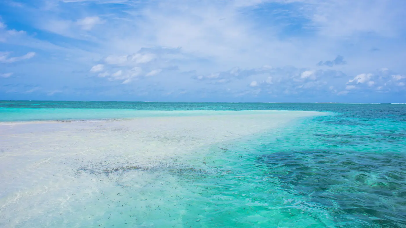 Serene beach with clear turquoise water and open sky, perfect for relaxation and travel inspiration.