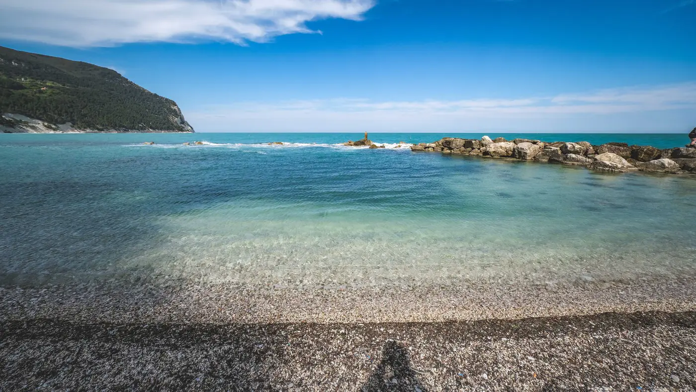 Serene beach view featuring turquoise waters, rocky shorelines, and a vivid blue sky.