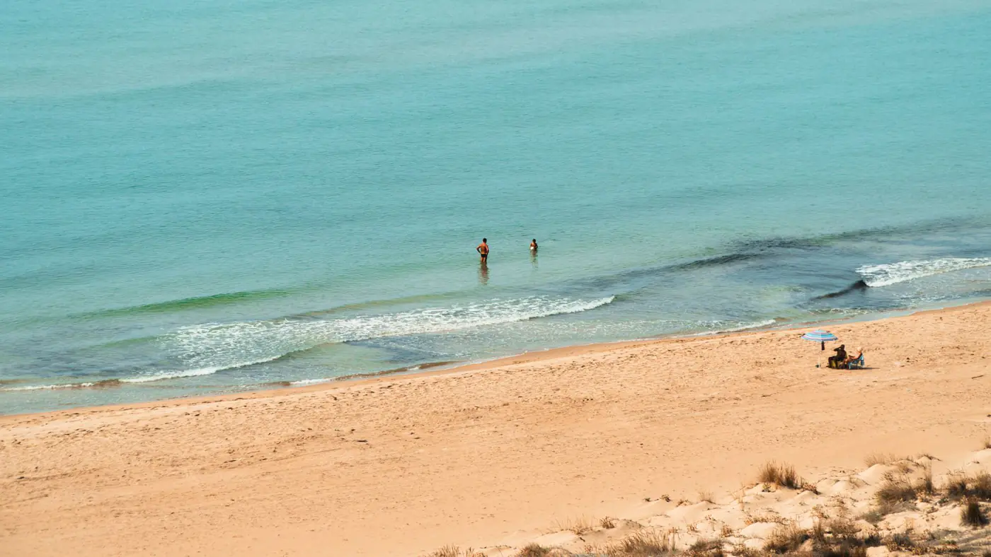 Peaceful beach day with people swimming and sunbathing in Comiso, Sicily.