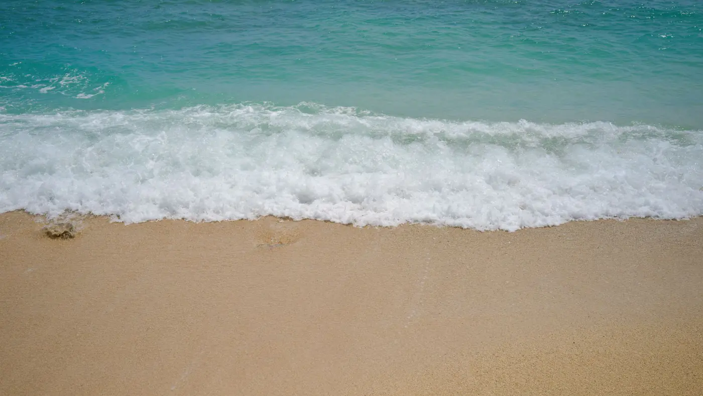 Peaceful ocean waves meet a sandy shore, perfect for a tranquil beach getaway.