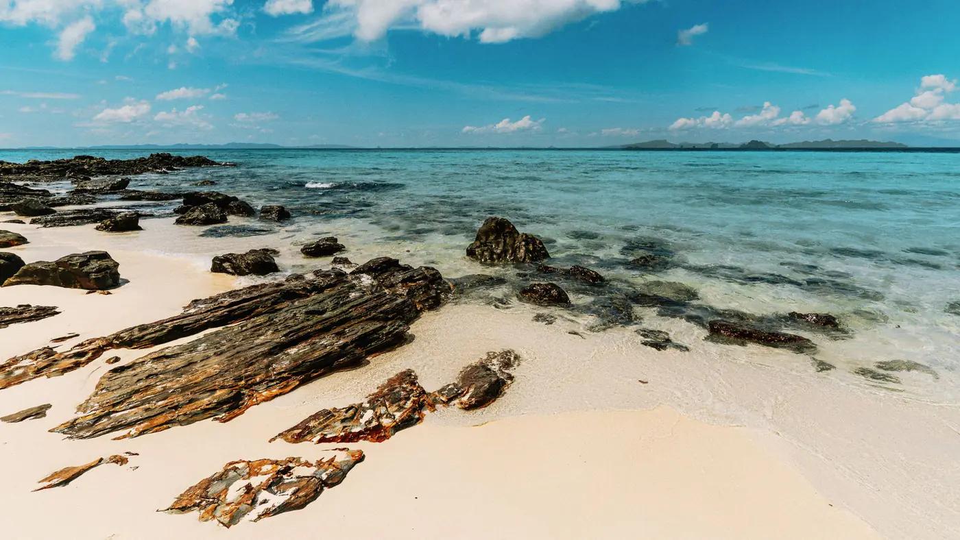 Tranquil beach with rocks and turquoise waters in Ao Nang, Krabi, Thailand.