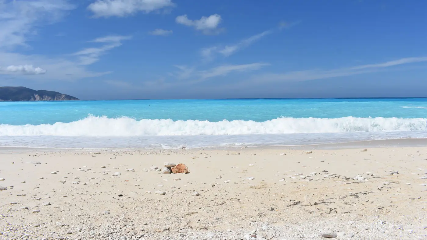 Serene beach view at Myrtos Beach, Kefalonia, Greece with clear blue skies and turquoise waters.
