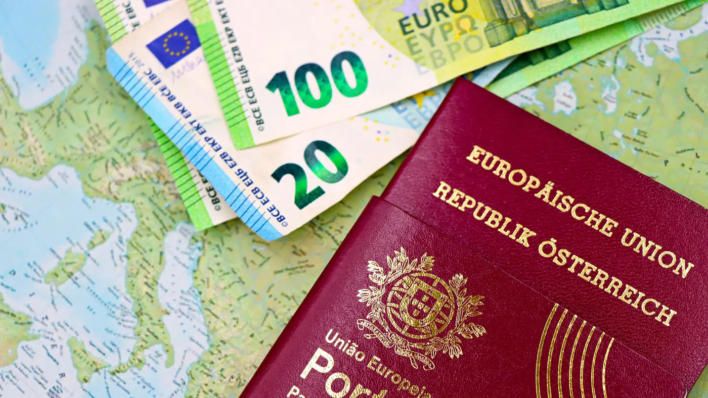Portugal and Austria passports displayed with Euro currency notes on European map background.