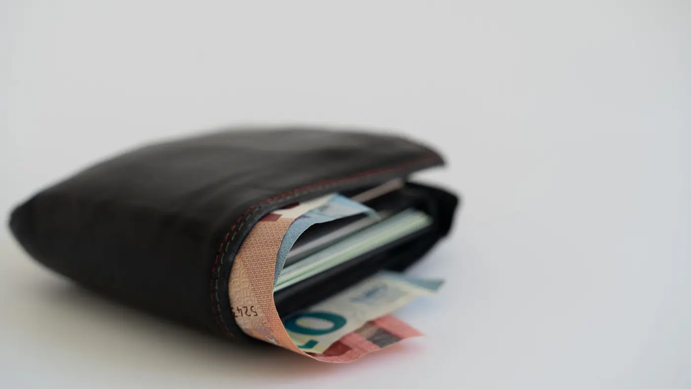 Close-up of a leather wallet filled with Euro banknotes on a white background, perfect for financial and lifestyle themes.