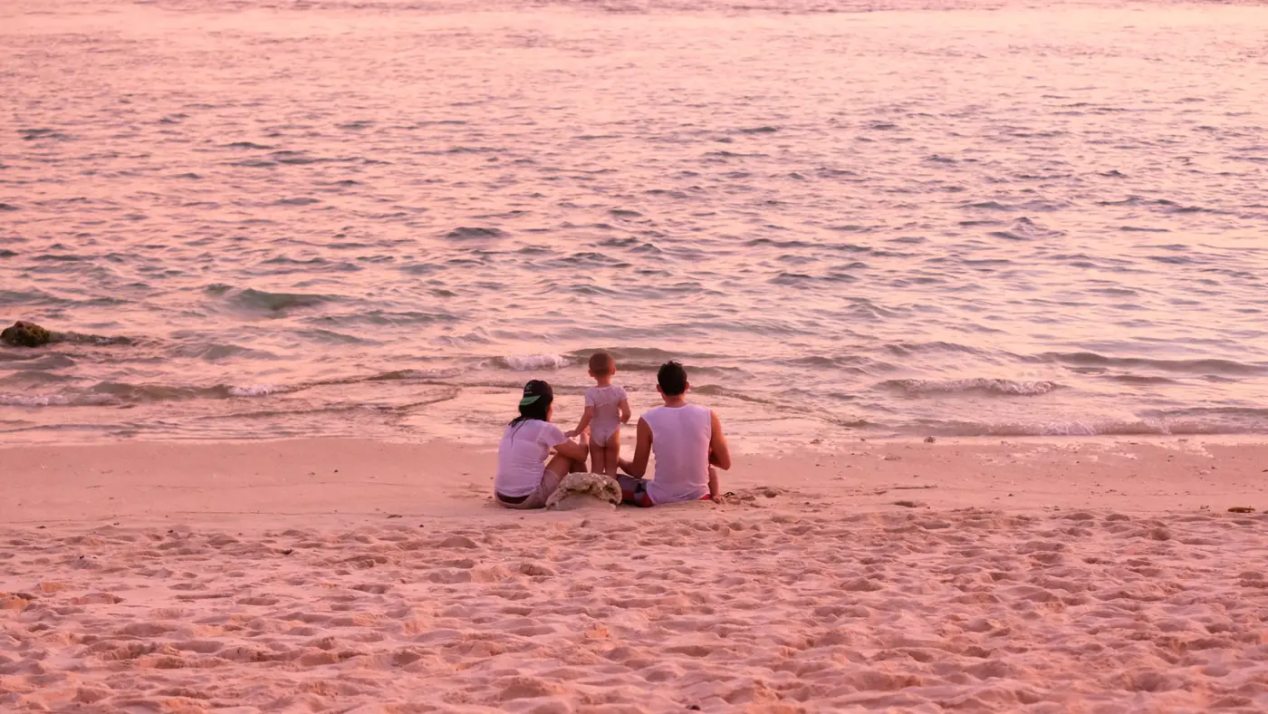 A serene family moment at the beach during sunset, capturing the tranquil atmosphere and pastel hues.