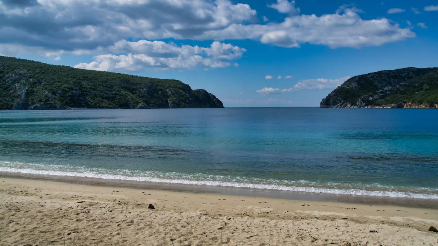 Peaceful Greek beach scene with turquoise waters and a clear blue sky, ideal for summer vacations.