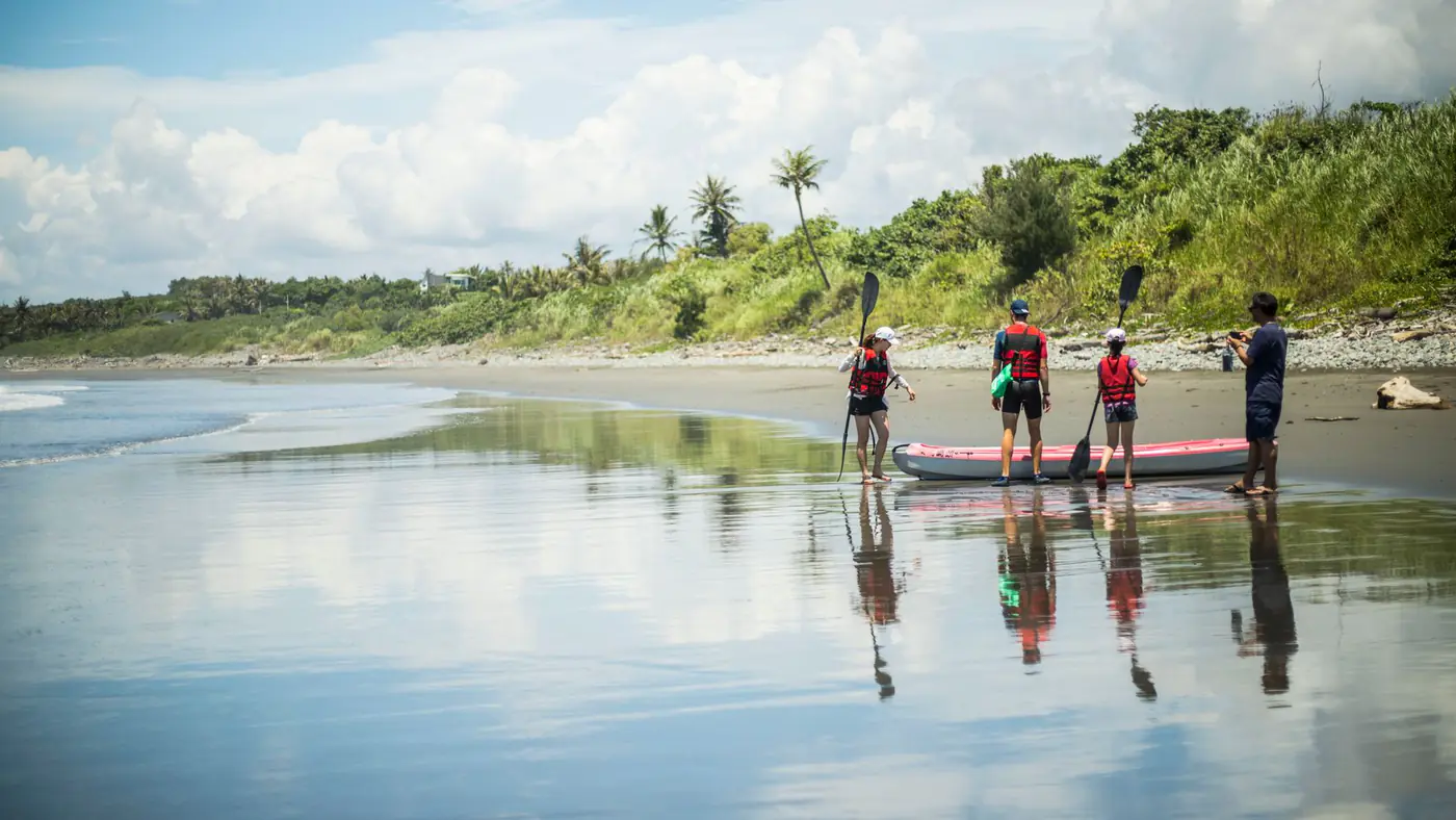 A family enjoys paddling on a picturesque beach in Taitung, Taiwan, during a sunny day.