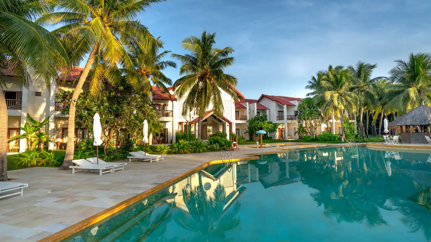 Luxury resort poolside view with palm trees, offering a tropical and serene escape.